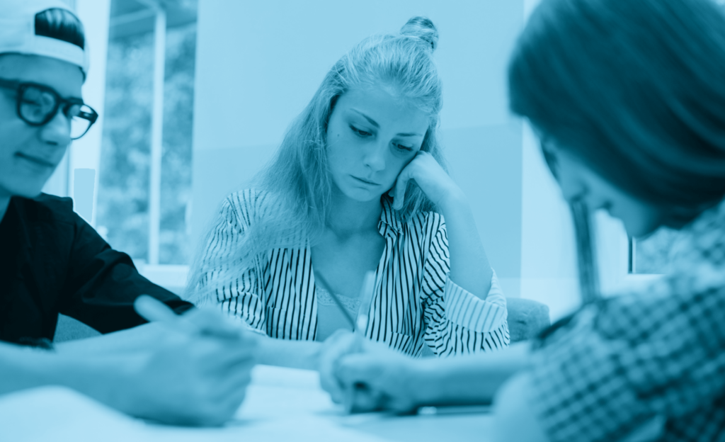 Foto di una ragazza triste che studia con i suoi compagni